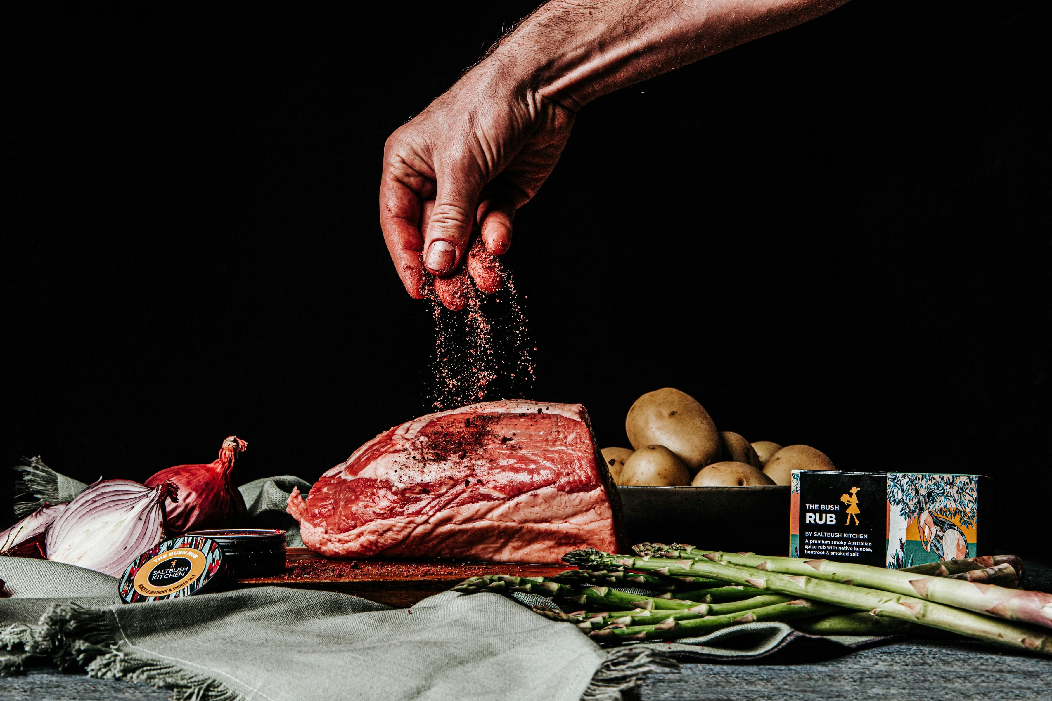 Sprinkling The Bush Rub over a prime roast beef.