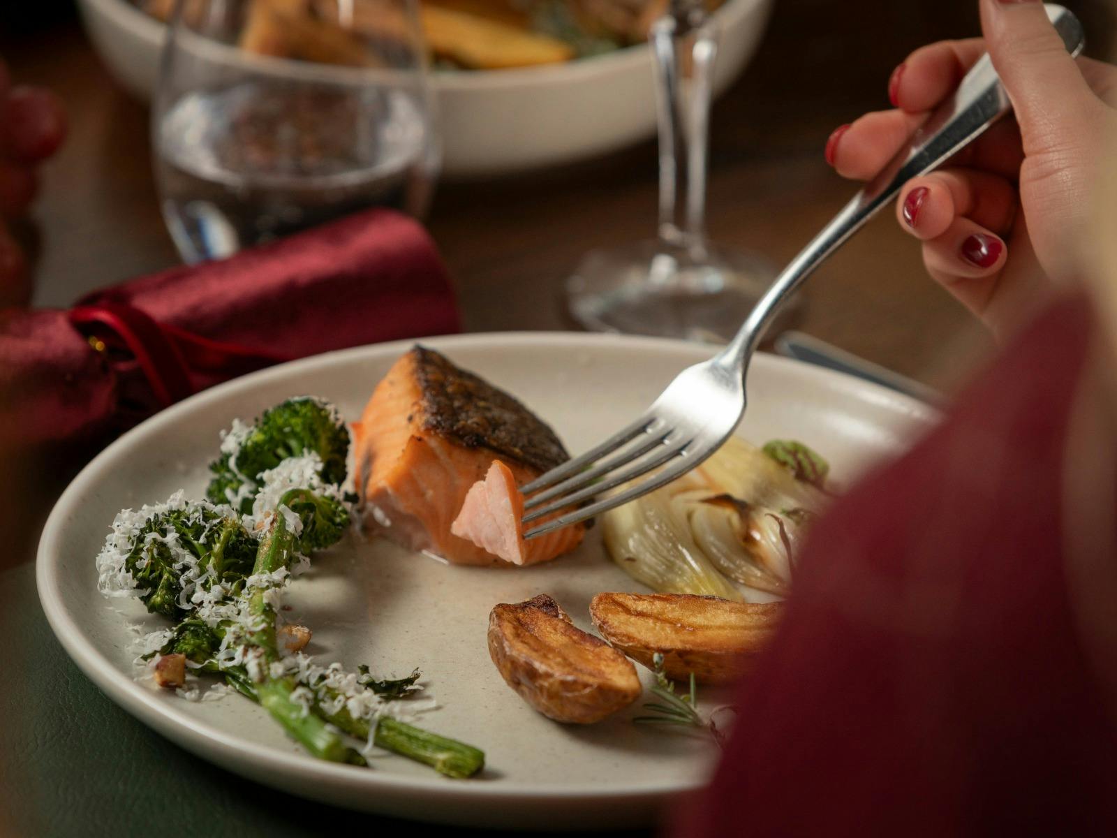 Plate of food from a buffet dinner service and a person eating the food with a fork