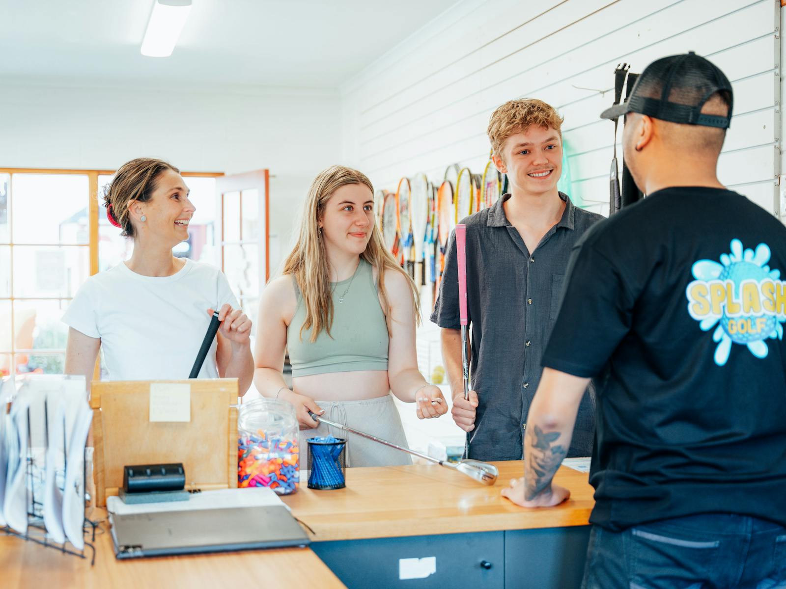 Three smiling guests being served in the activity centre by Tamar Valley Resort staff member
