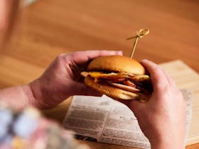 A woman holds a breakfast burger with egg, cheese and bacon