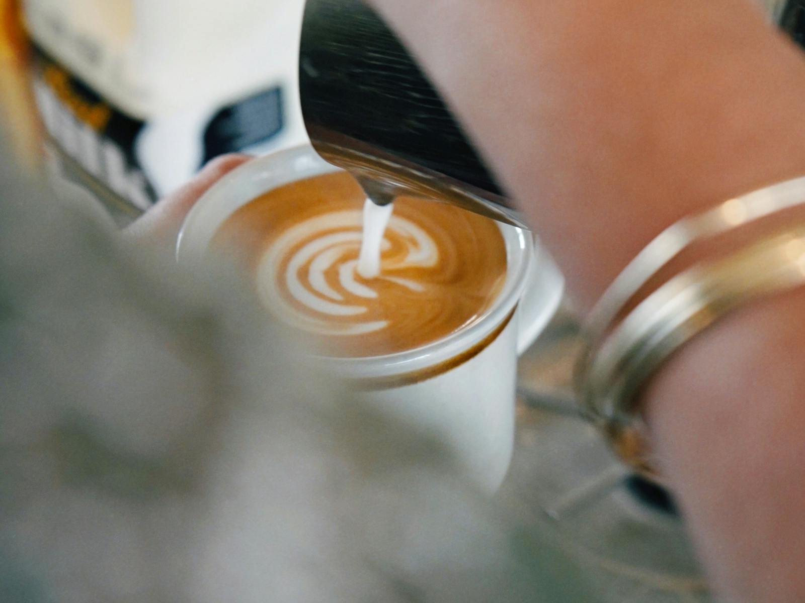 A flat white coffee being poured at Sunbear cafe