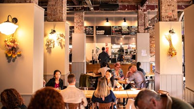 Food hall with people sitting beside columns with lights and dried flowers