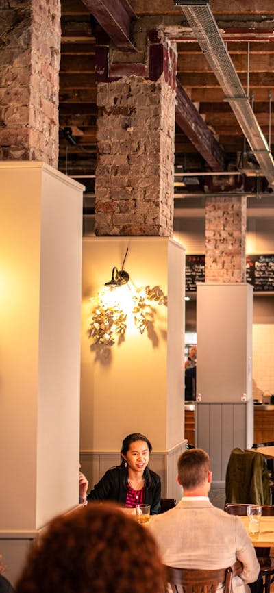 Food hall with people sitting beside columns with lights and dried flowers