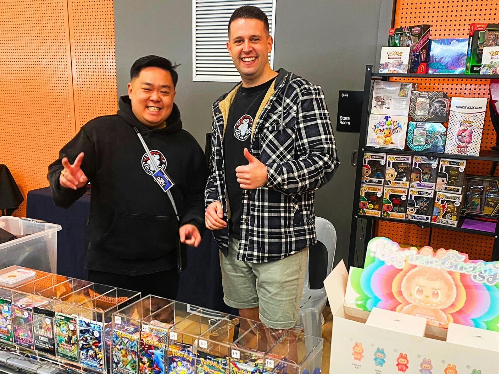 Two vendors smiling at their trading card stall