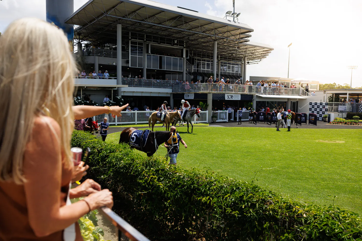 wide shot of the mounting yard with people viewing horses parading