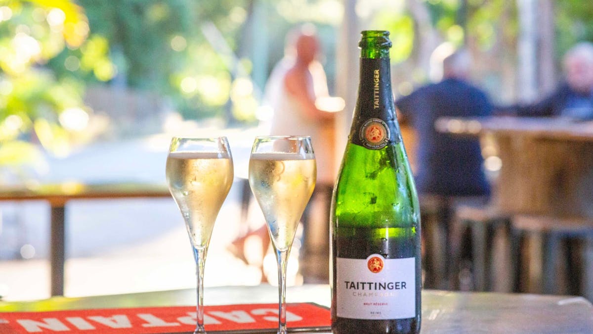 Bottle of Taittinger Champagne on ice with glasses ready to pour at Dingo Beach Pub.