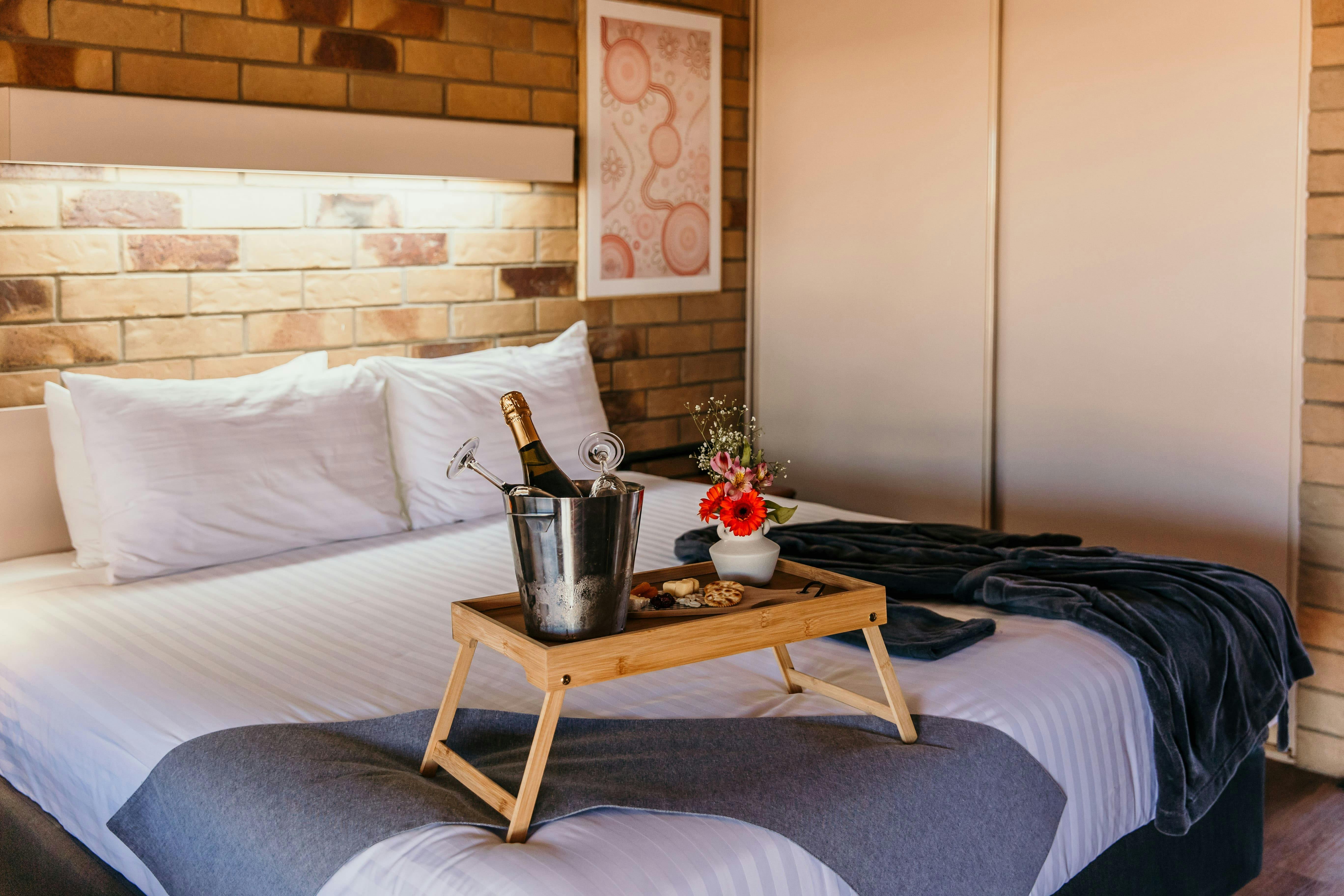 King bed with a robe, cheese platter and champagne ice bucket.