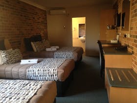 Three beds on right with bathroom in background and desk, Tea/coffee making facilities area on right