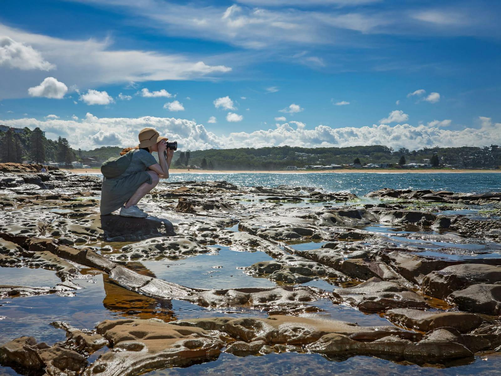 Guest photographing rocky coastline and ocean scenery on a sunny day near Sydney.