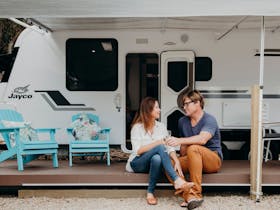 Couple sitting in front of a caravan