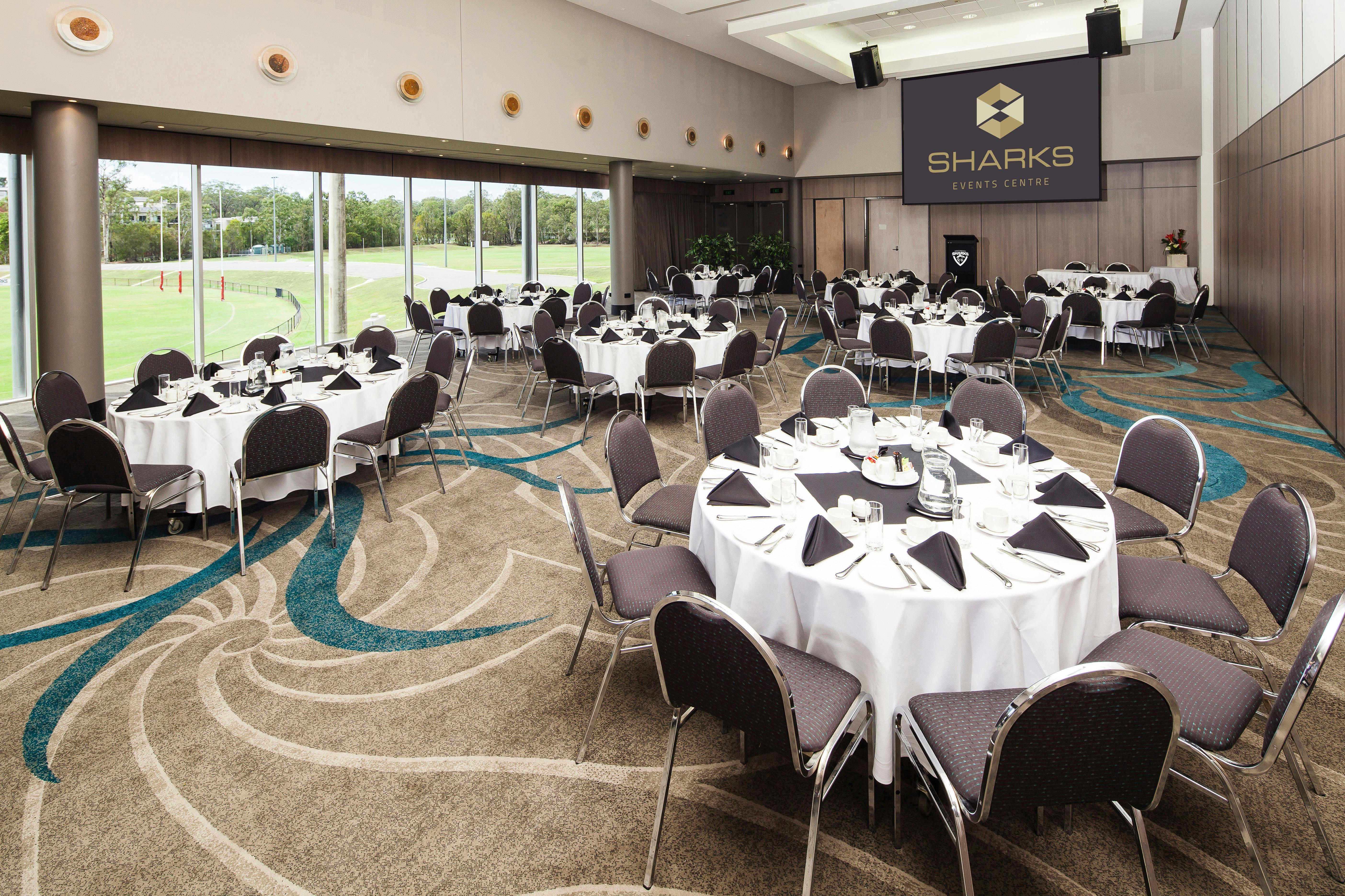 A function room prepared for a corporate breakfast with tables and chairs arranged