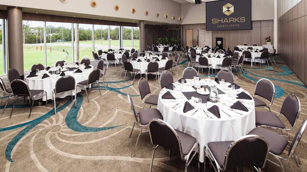 A function room prepared for a corporate breakfast with tables and chairs arranged