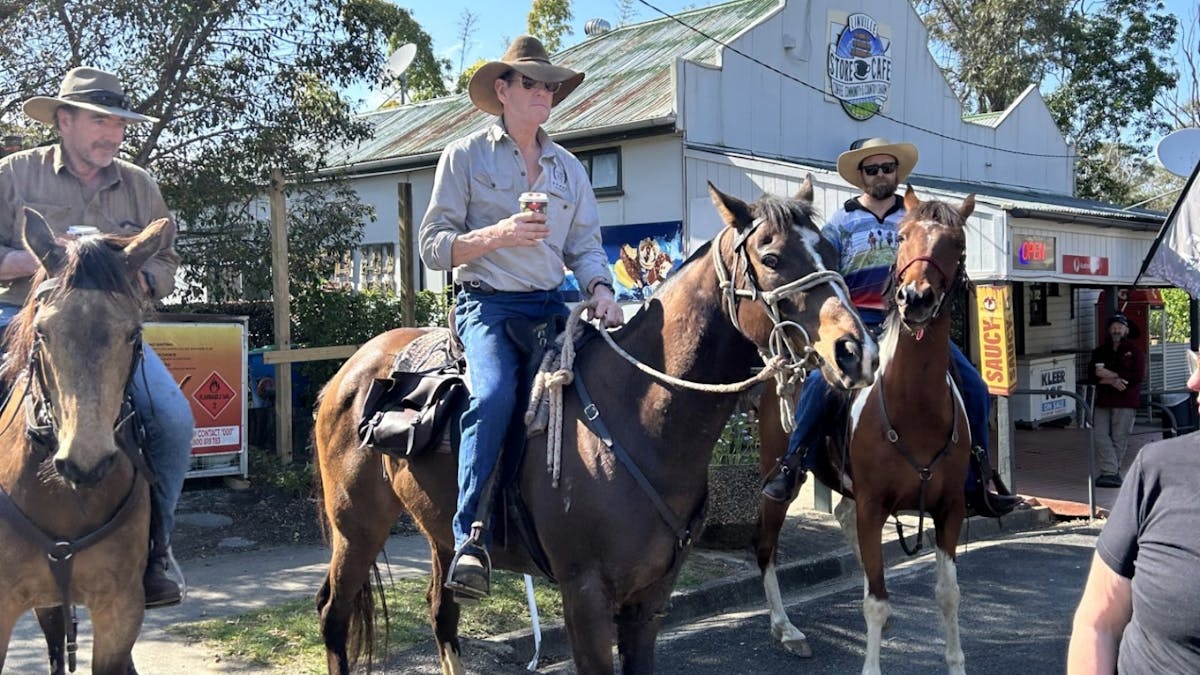 Several horse riders holding takeaway coffees, gathered outside the Linville Store & Café