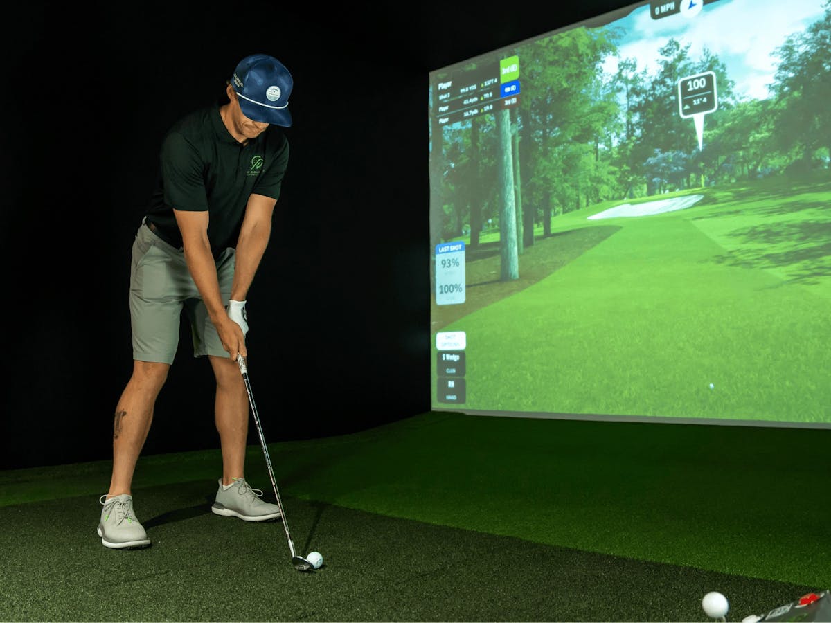 Male golfer lines up his swing for a shot in the golf simulator Male golfer lines up his swing for a shot in the golf simulator