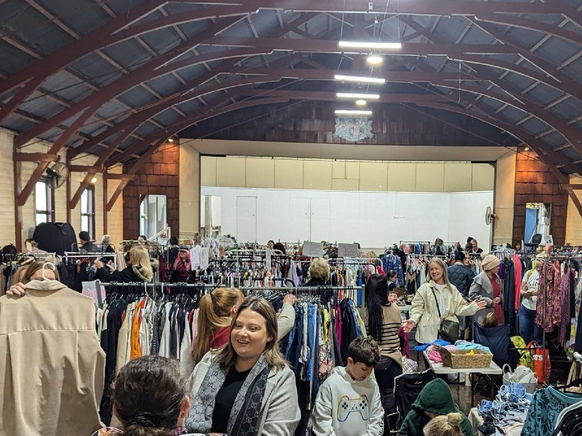 People walking around a hall with racks of clothes