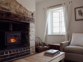 Living room with original stone fireplace and wood fire at 1856 Cottage in Robe South Australia