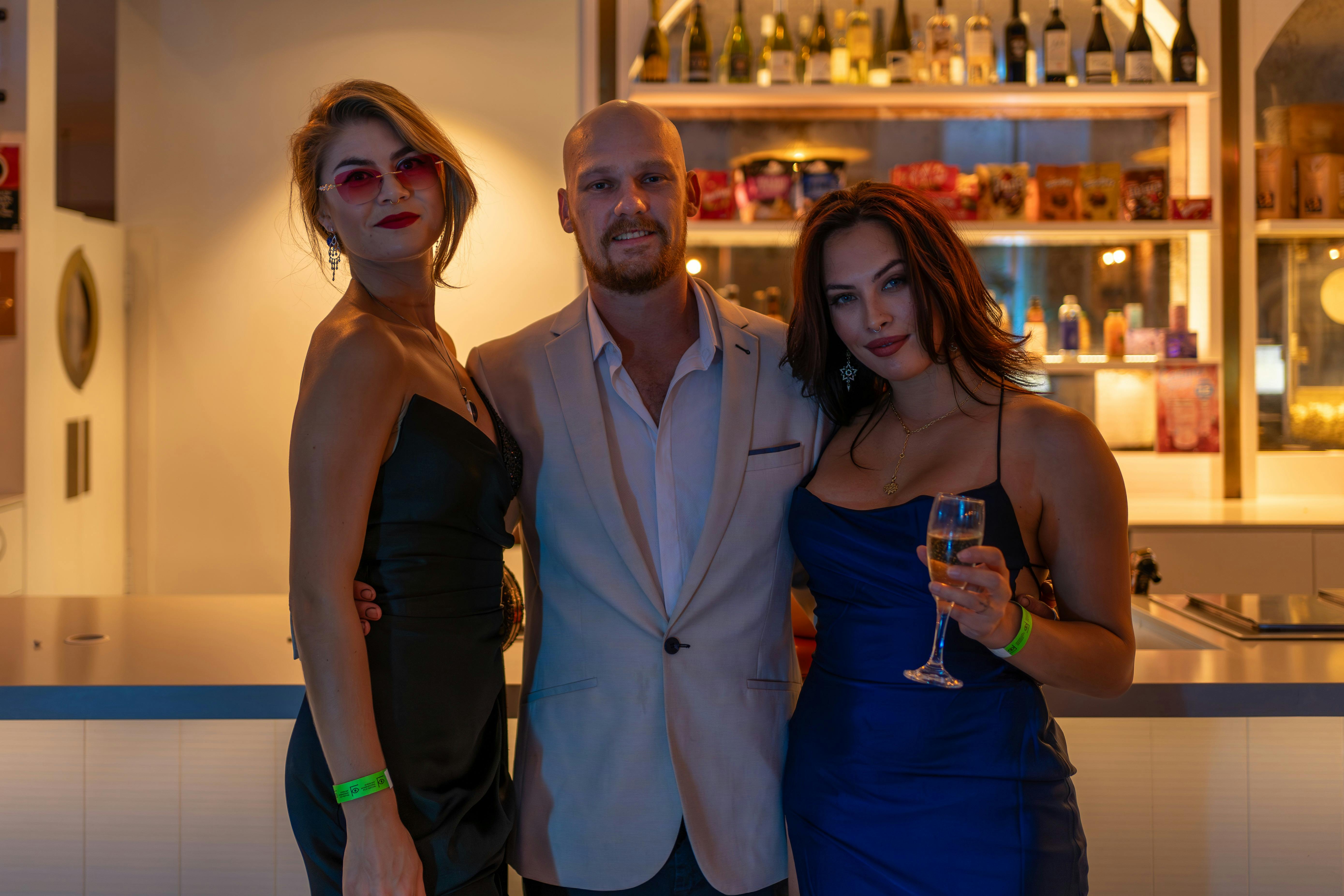 A man and his 2 women friends look very glamourous as they enjoy a drink at the Opening Night