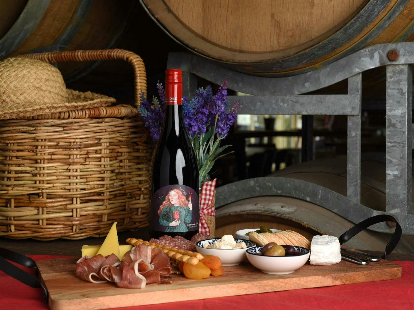 cheese and meat platter with a bottle of red wine picnic basket