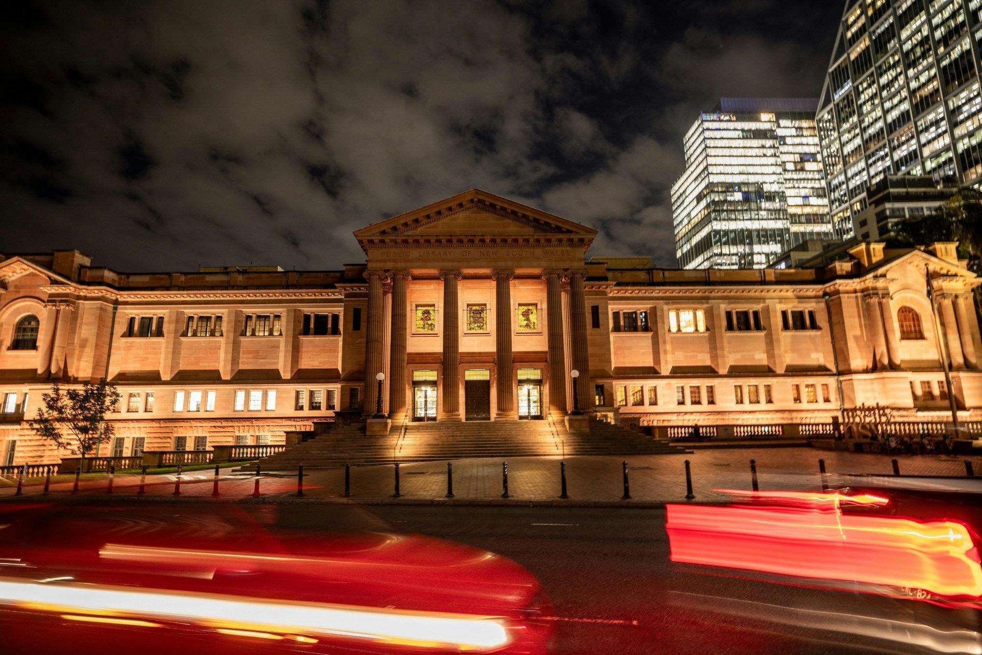 A grand sandstone building lit up at night time