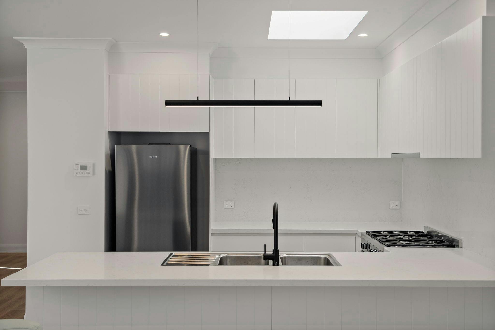 Kitchen with white bench tops, appliances and skylight
