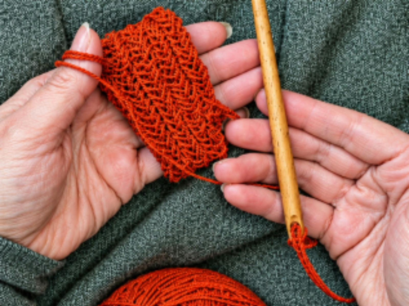 Pair of hands holding knitted yarn in one and a needle in the other