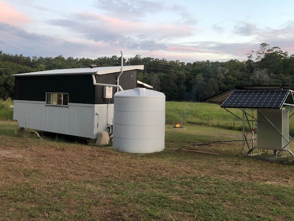Rear side of tiny house with beehive paddock on the left and power station on the right.