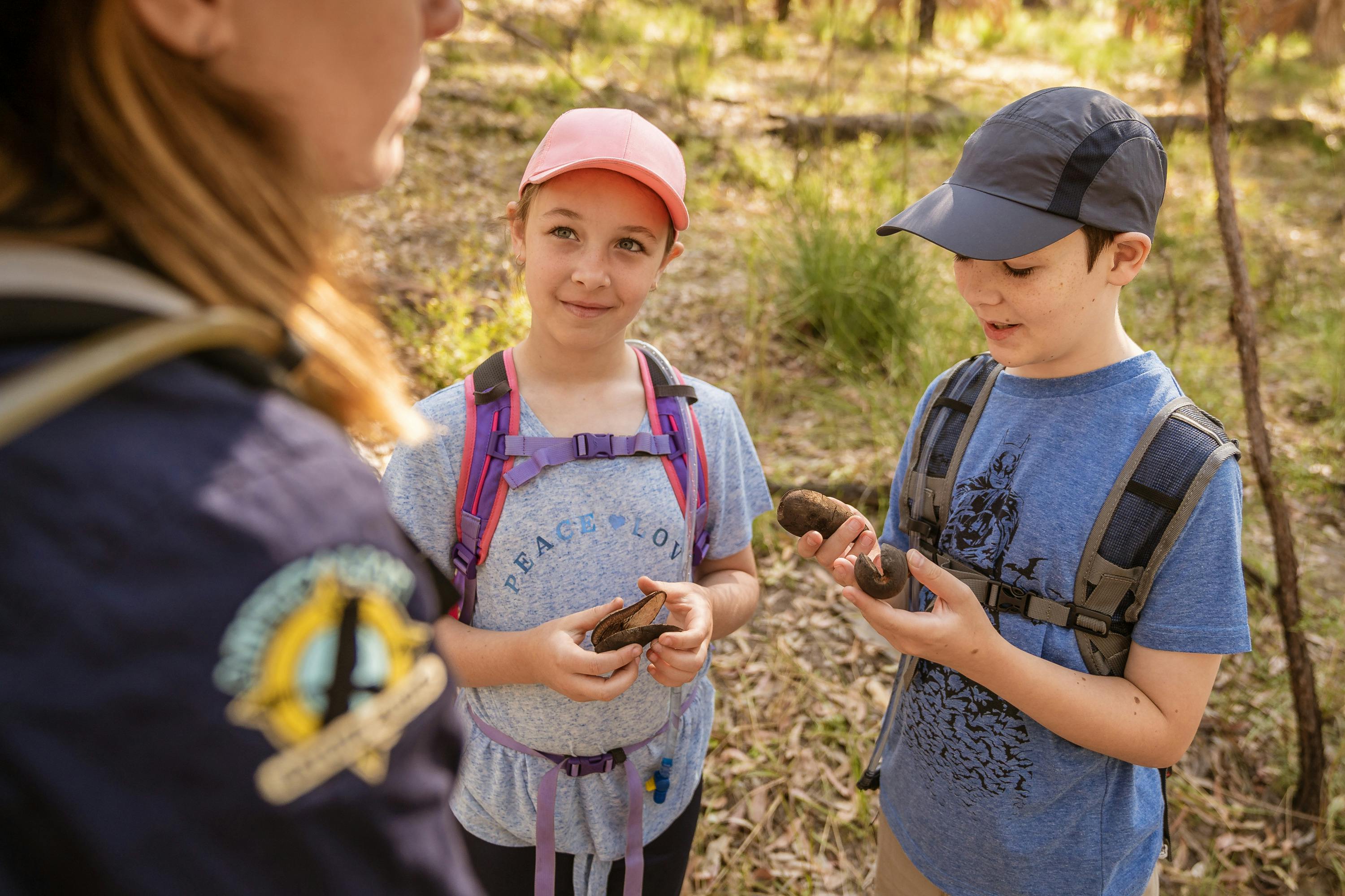 A tour guide and two children inspecting the large seed pods from the woody pear at Carnarvon Gorge.