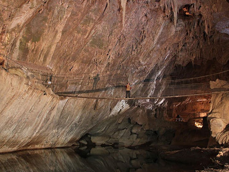 A visitor walks across a swing bridge in Belfry Cave at Abercrombie Karst Conservation Reserve.