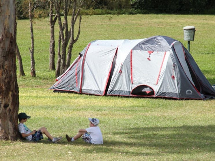 Children under a tree with their tent in the background at Bents Basin campground. Photo: John