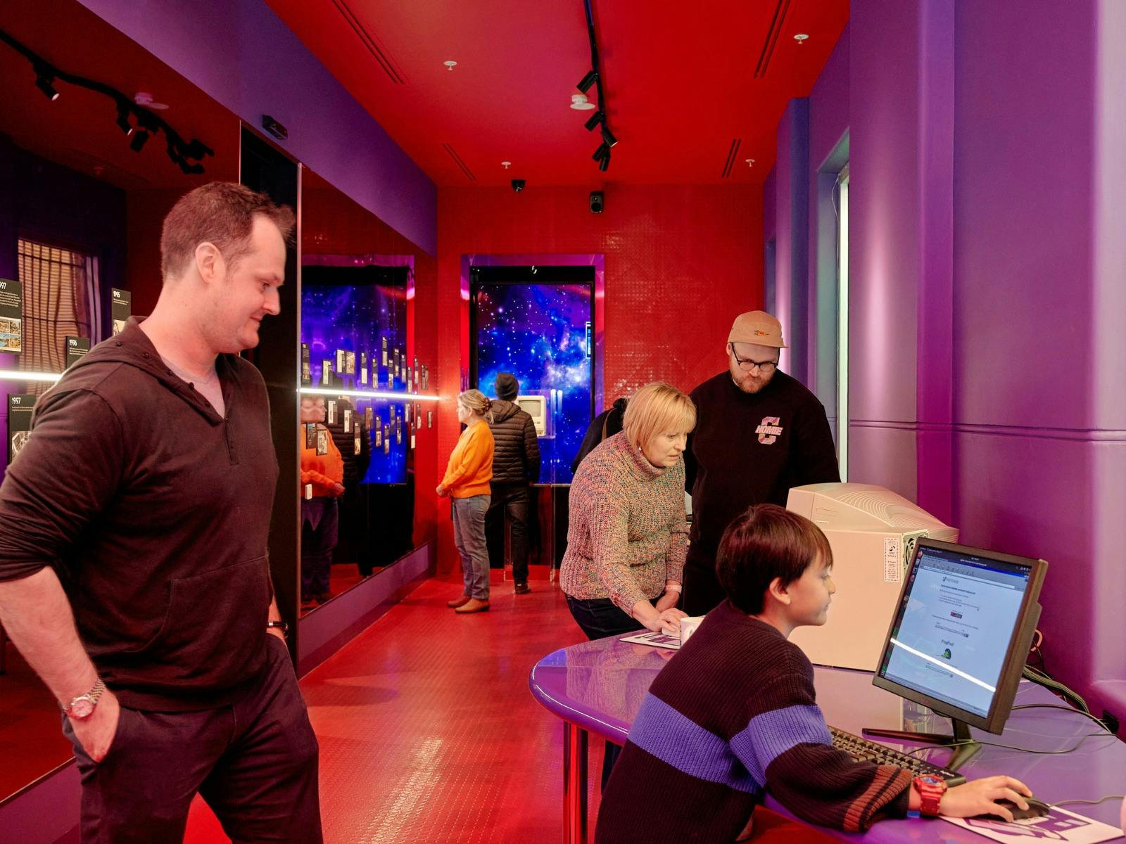 People playing on retro computers inside the brightly coloured, 90s-style Cyber Cafe