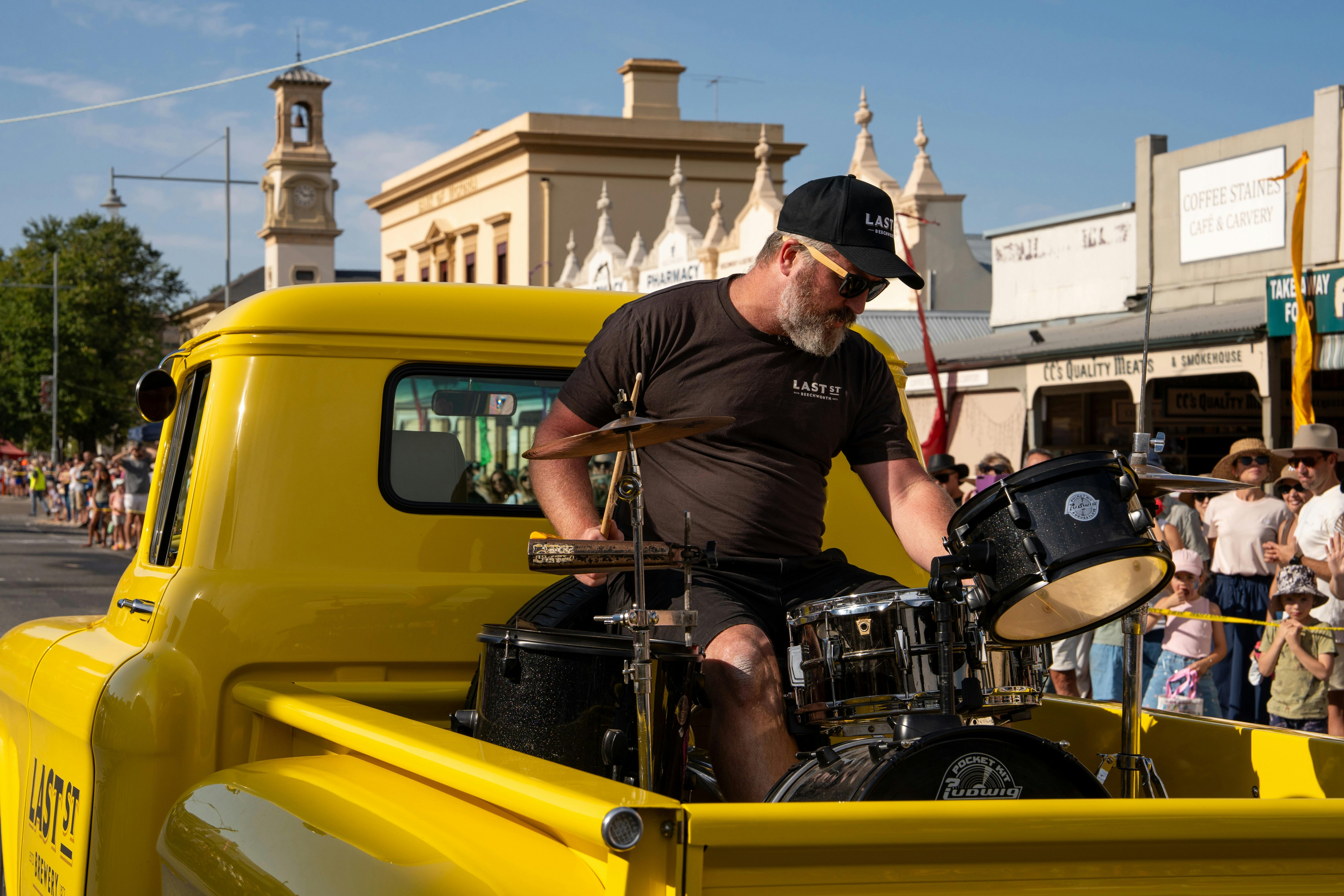 local drummer drumming on back of yellow ute for Last ST Brewery float