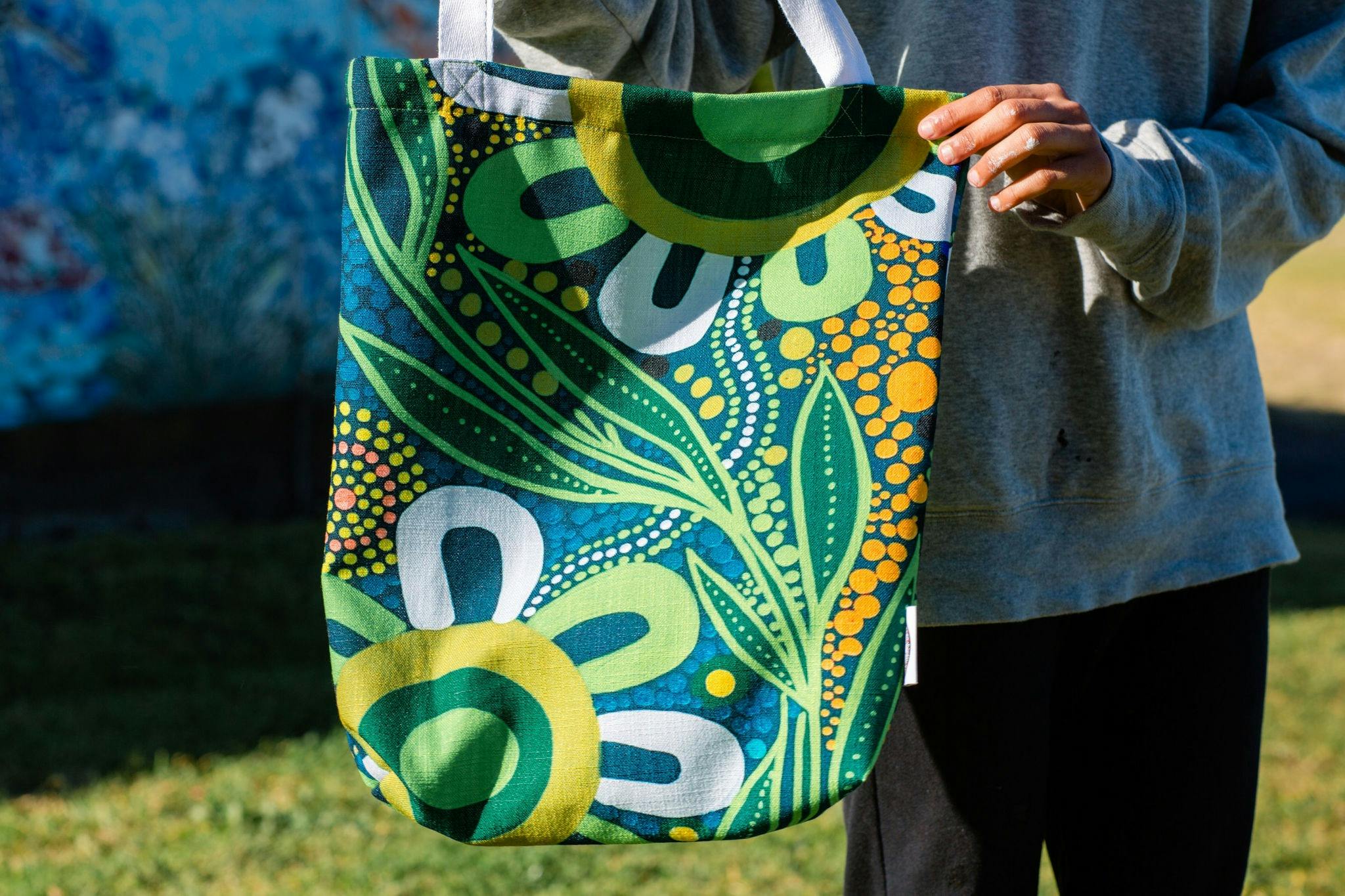 Person holding a colourful green tote bag