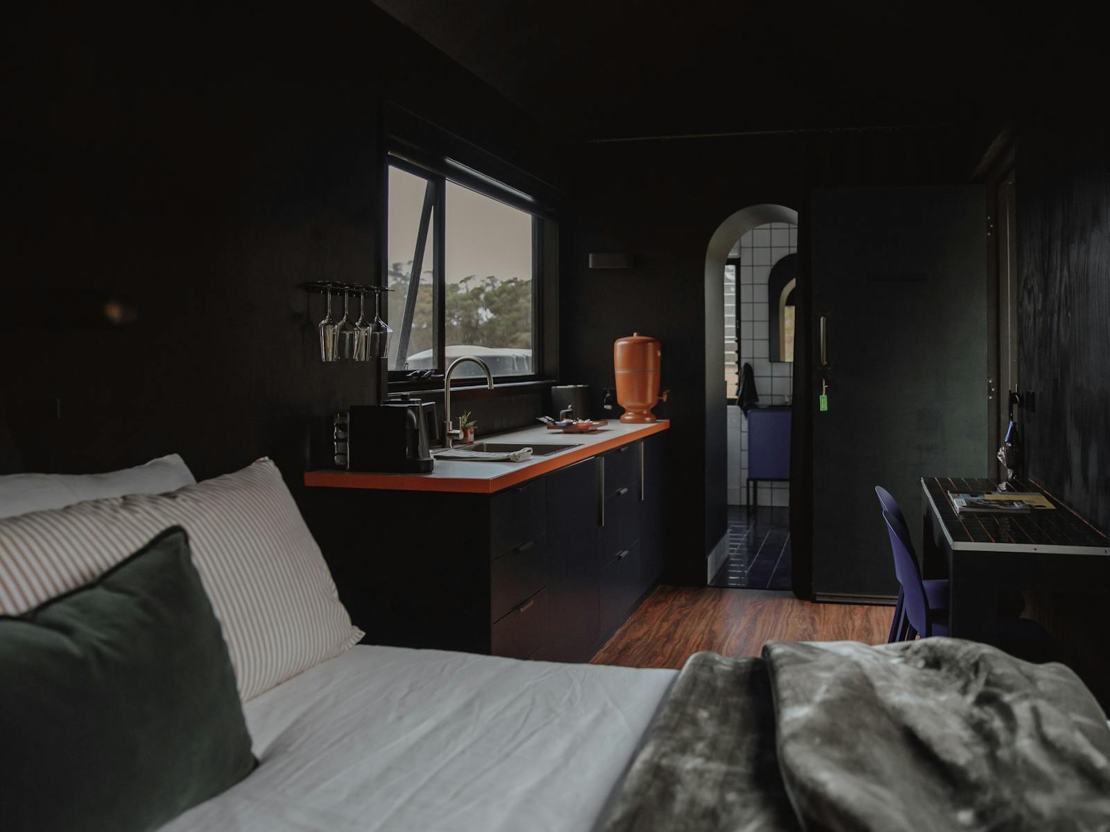 A queen bed in the foreground, kitchenette and bathroom