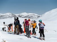 group on a snow capped mountain with snow gear and skis
