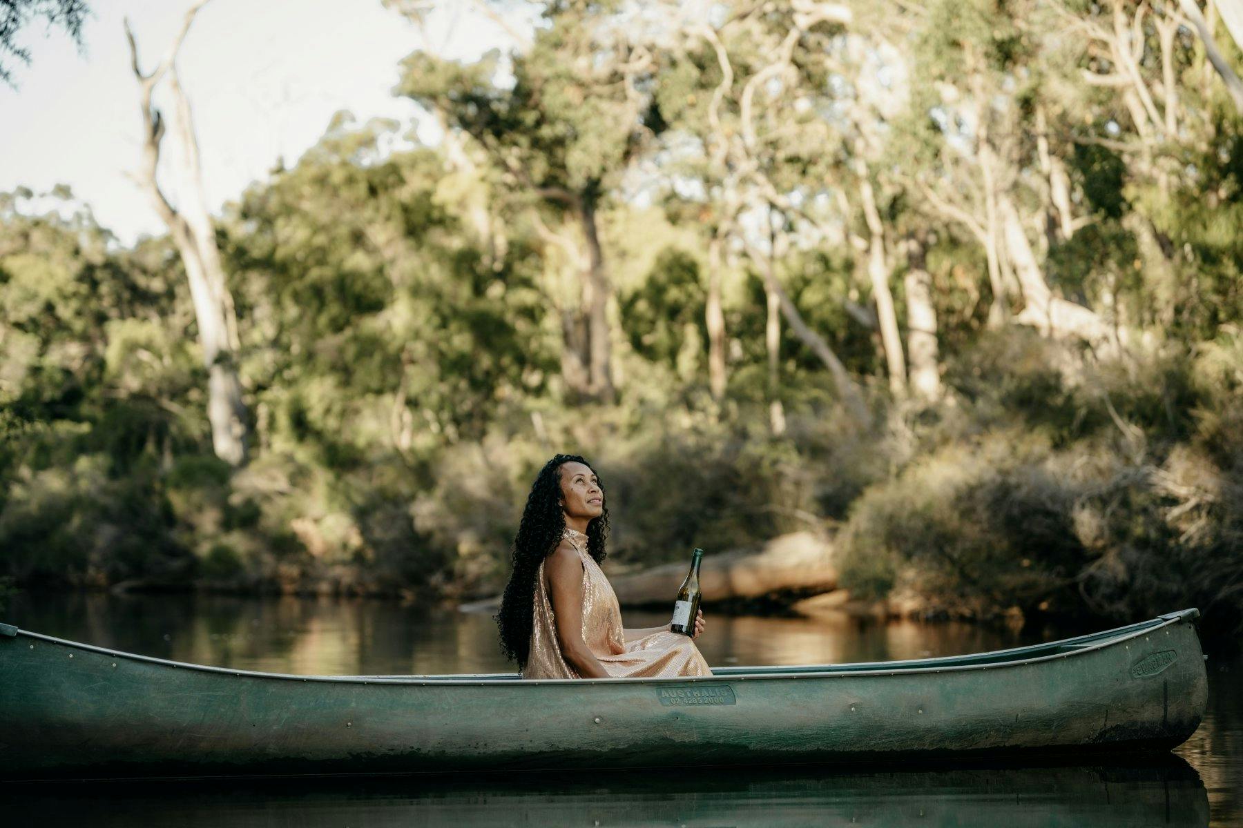 A woman sits beside the water under peppermint trees near Margaret River.