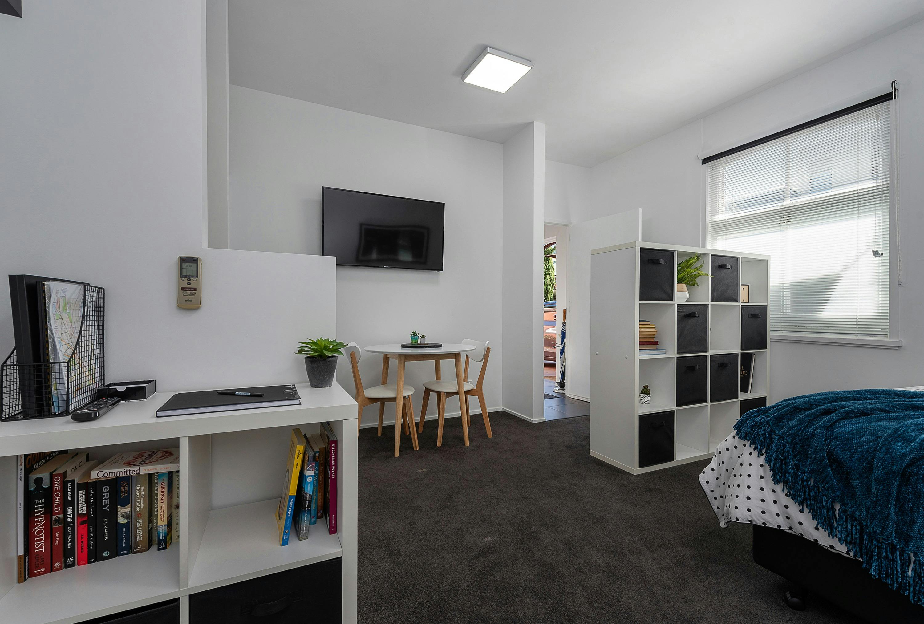Open-plan living and sleeping area with queen bed, lounge and dining area