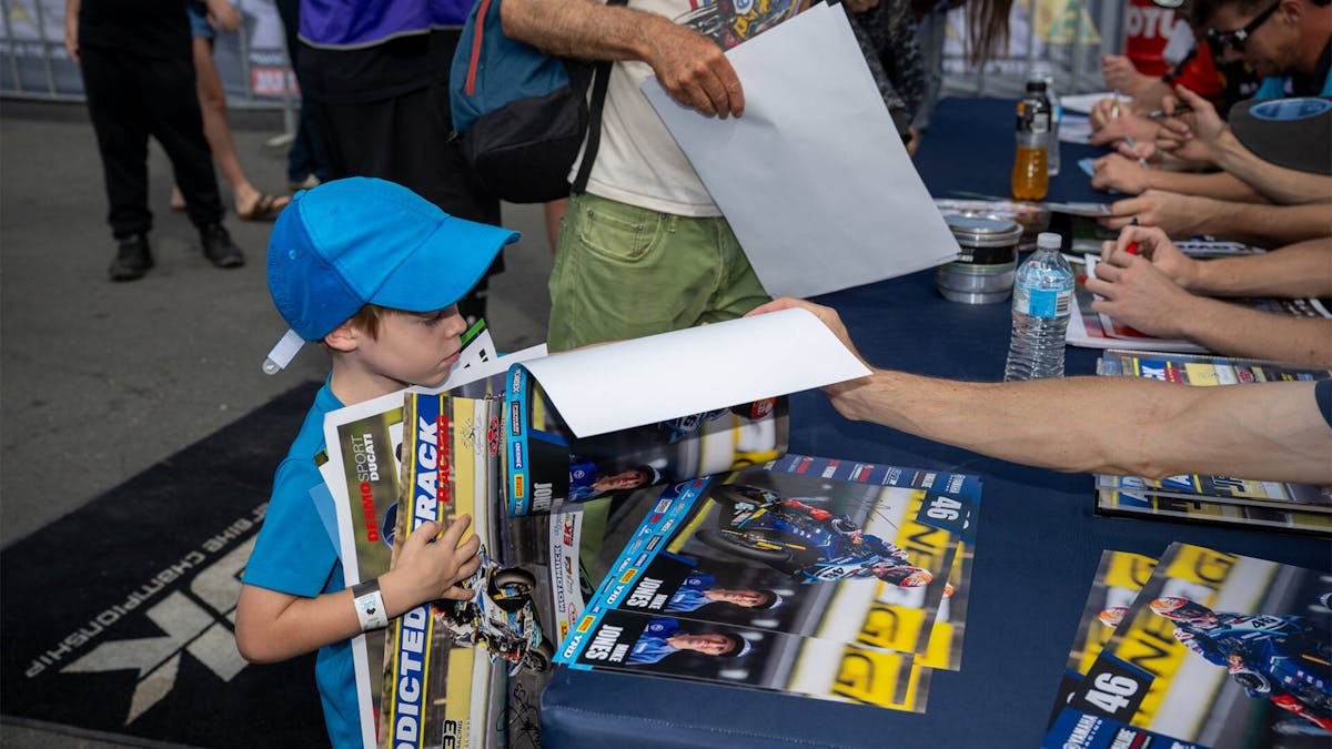 A child receiving a signed poster from riders at the signing session