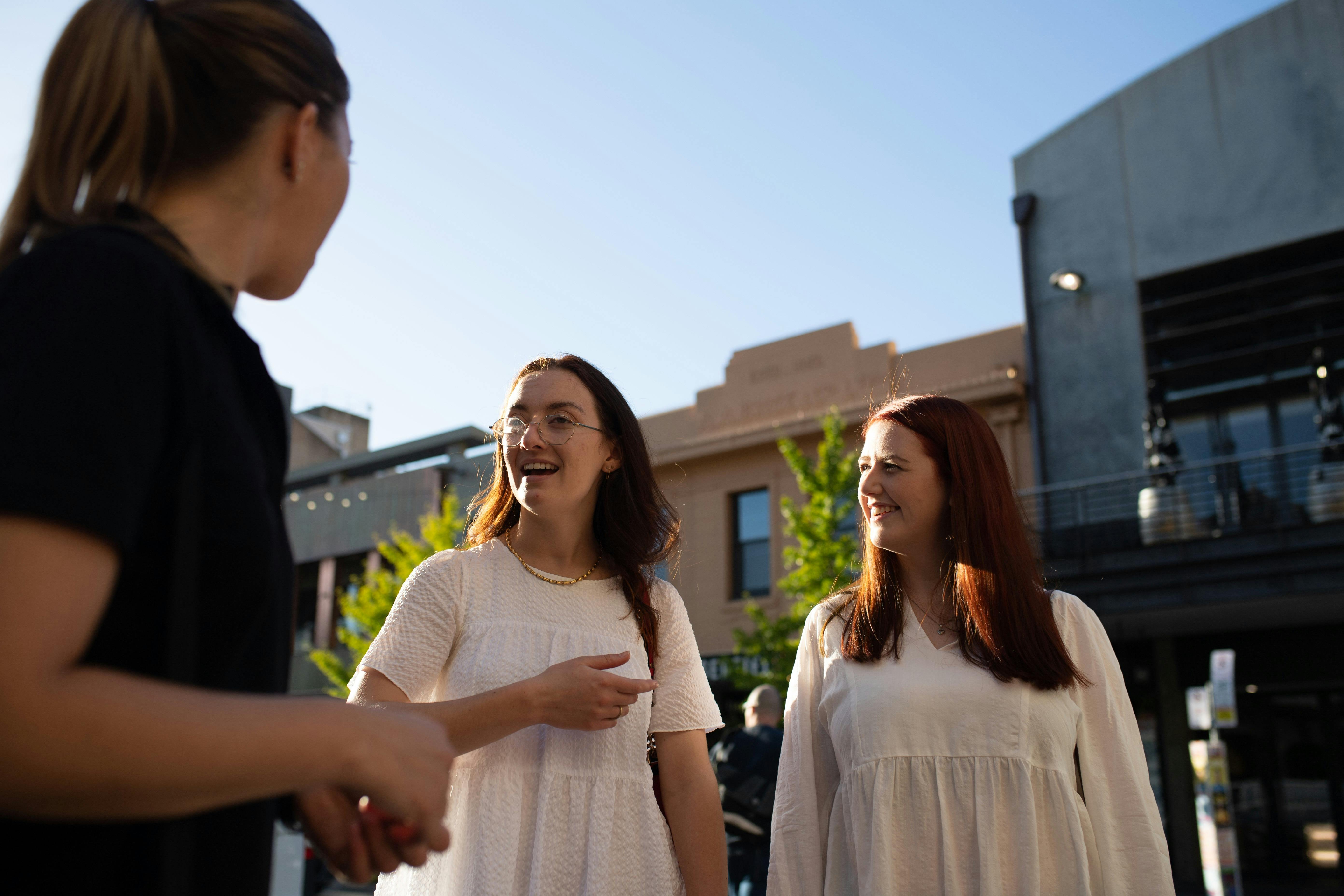 Two ladies in white chat with a tour guide.