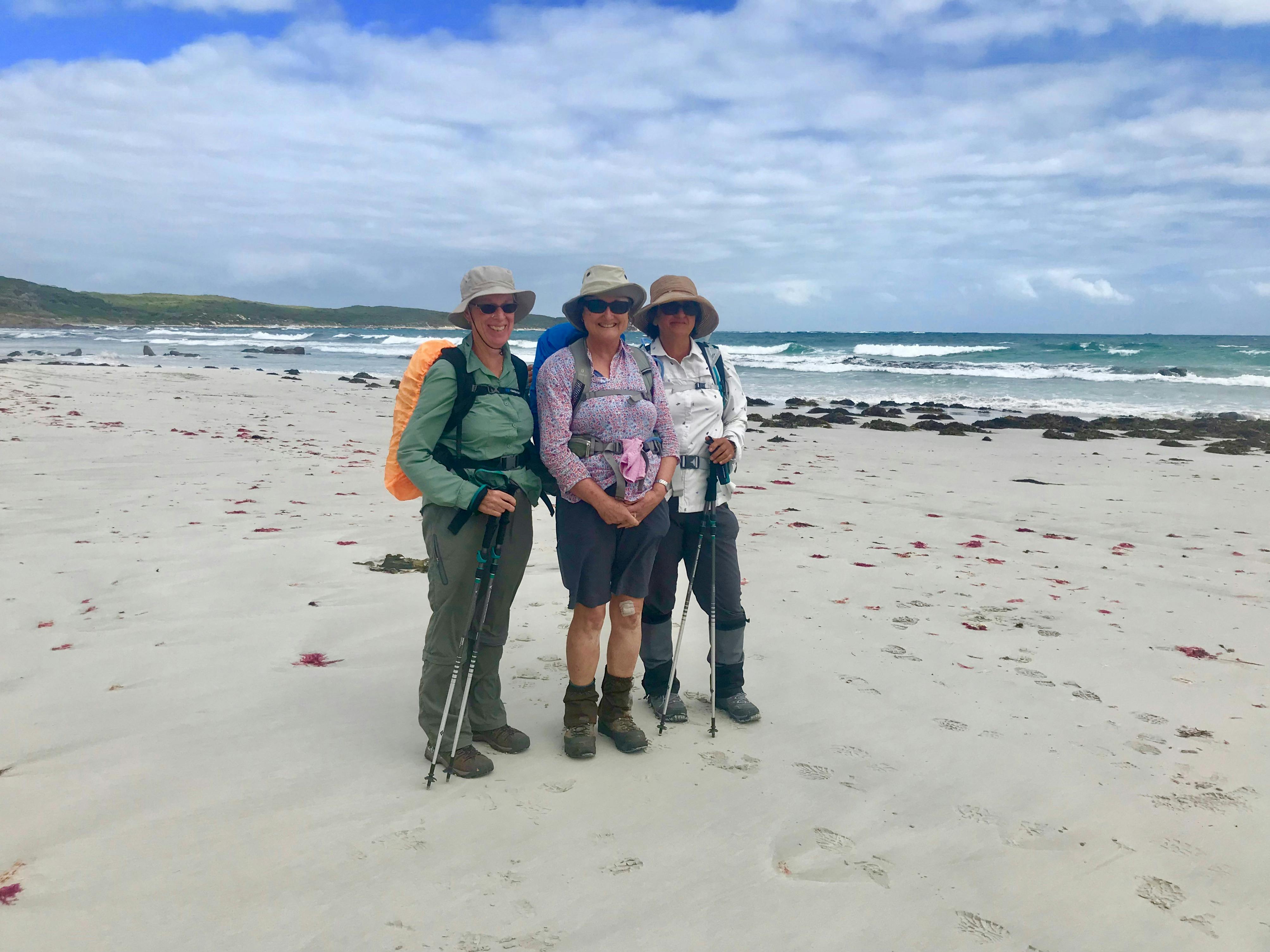 3 female hikers standing together on a beach