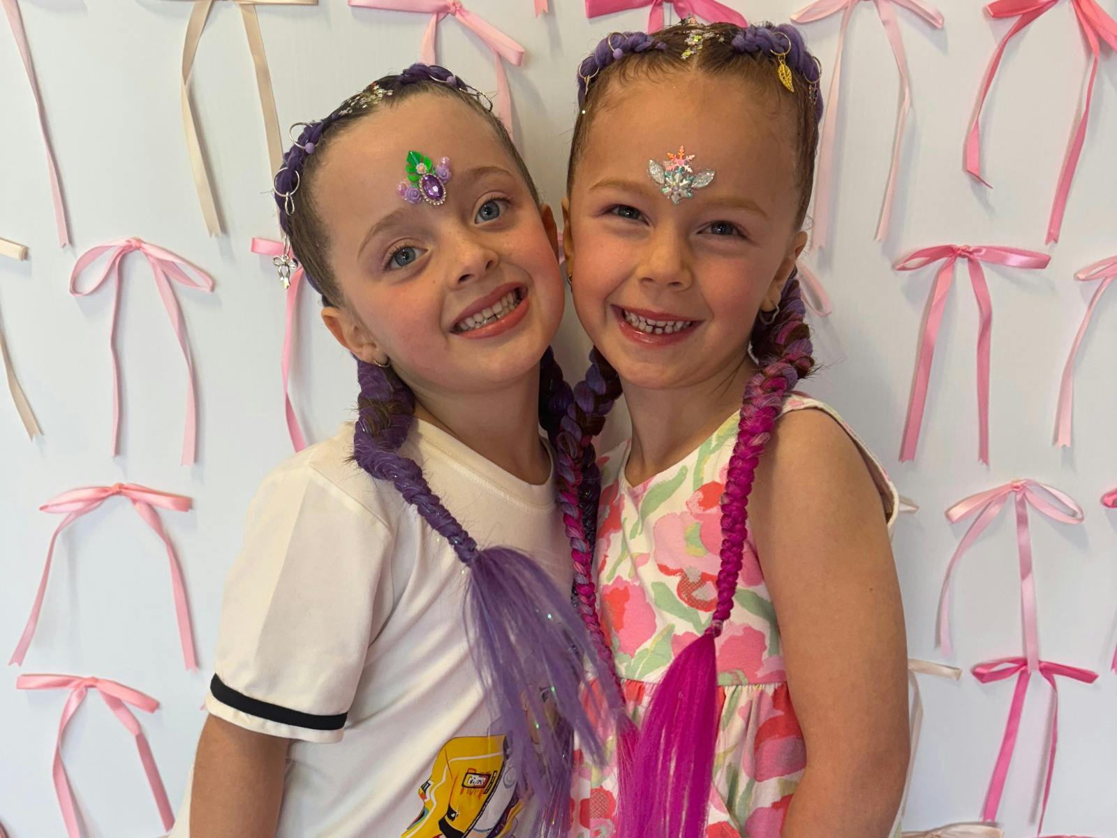 兩個有著紫色和粉紅色鬃毛的小女孩——辮子綁在馬尾辮上