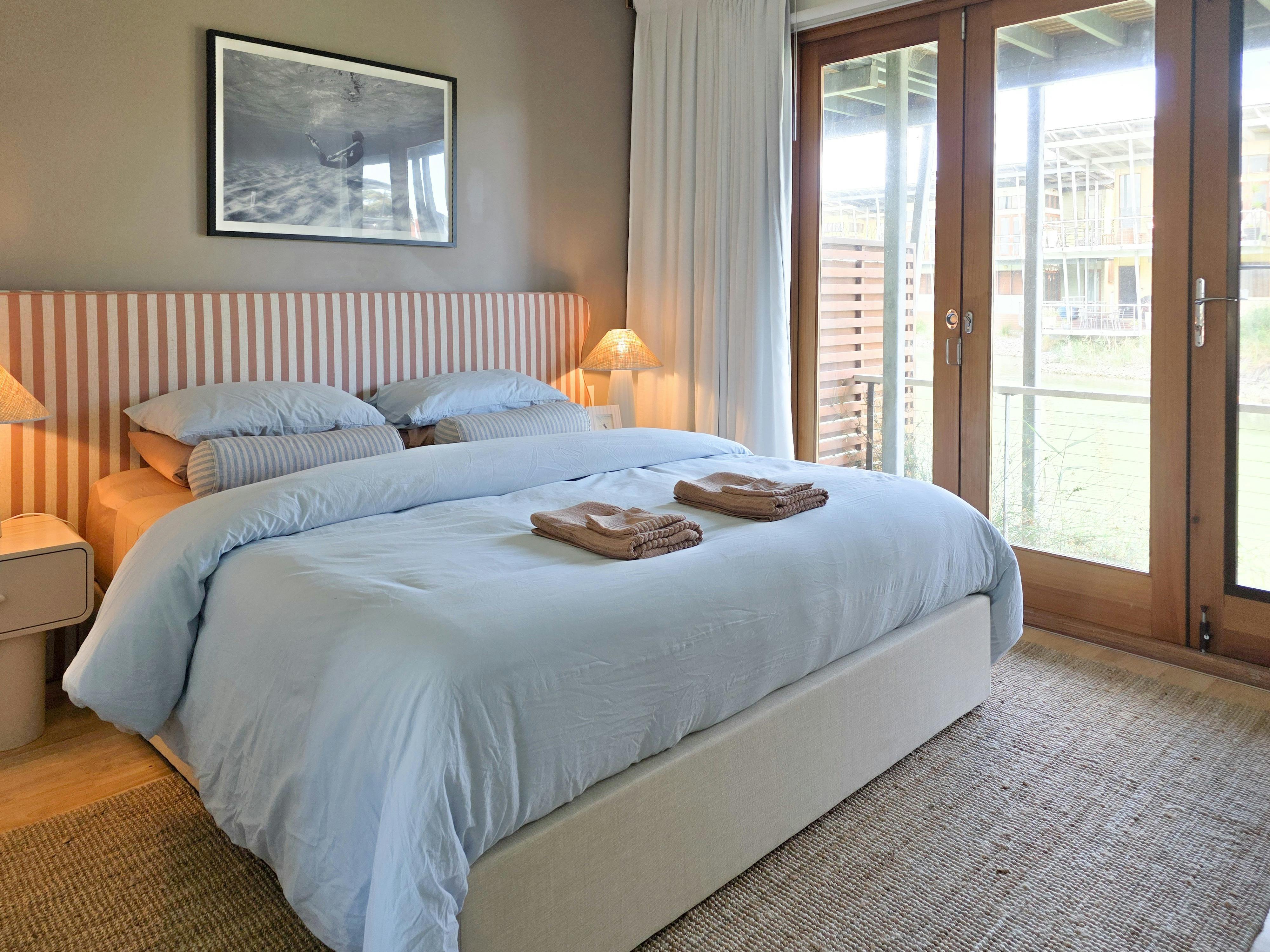 Light-filled bedroom with king bed, luxurious linen & lagoon views at The Pool House by The Shores