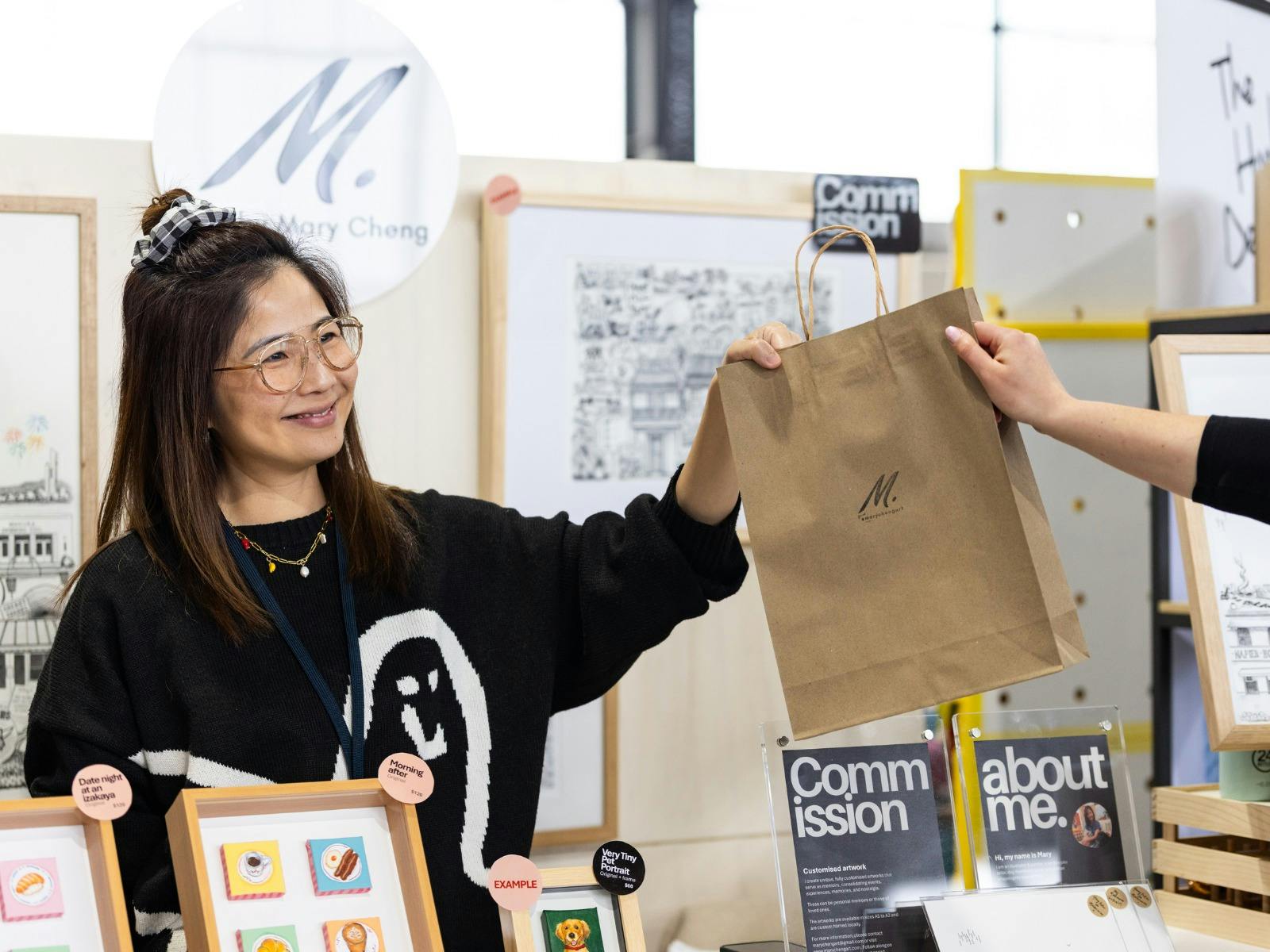 Mary Cheng Art handing a bag over to a customer