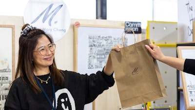 Mary Cheng Art handing a bag over to a customer