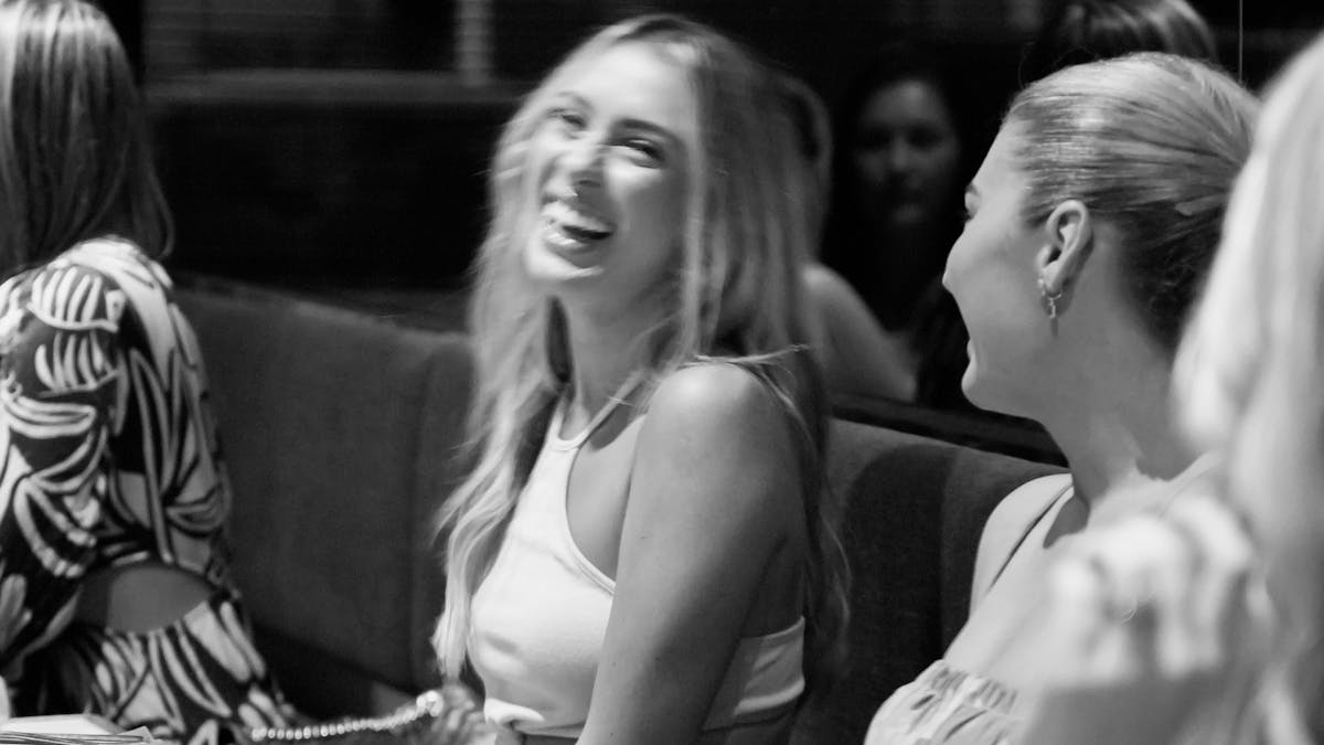 Two women are seated in restaurant, laughing and enjoying their time together.