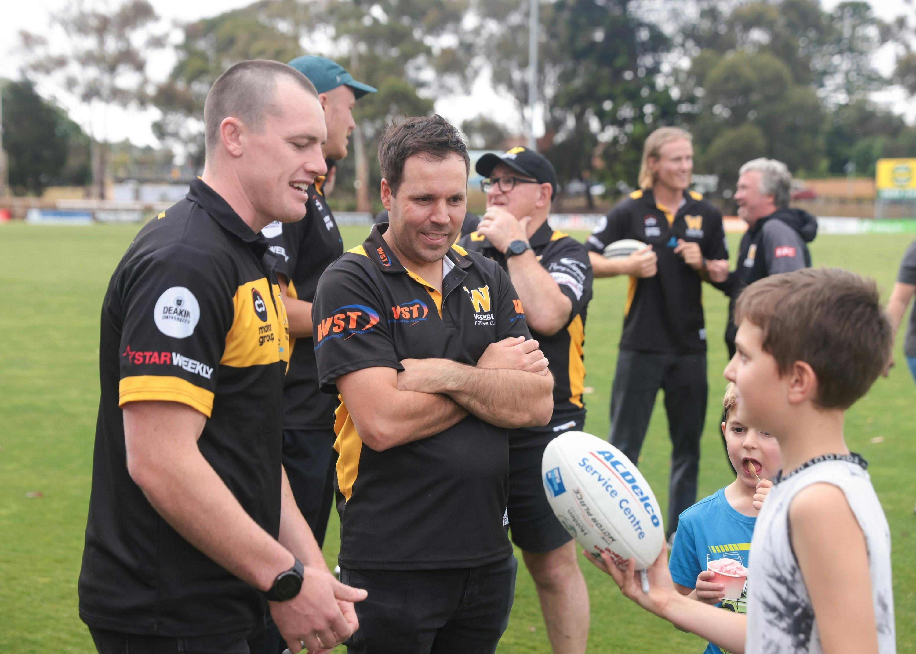 coaches chatting to child with football on ground