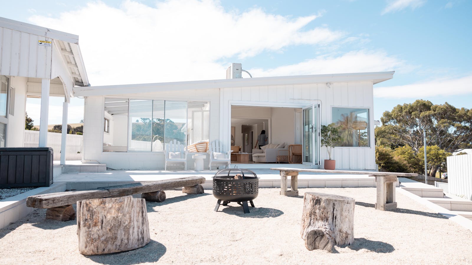 Outdoor fire pit area with wooden benches overlooking a calm ocean view