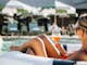 a woman sitting in an inflated tube in a pool with a glass of wine