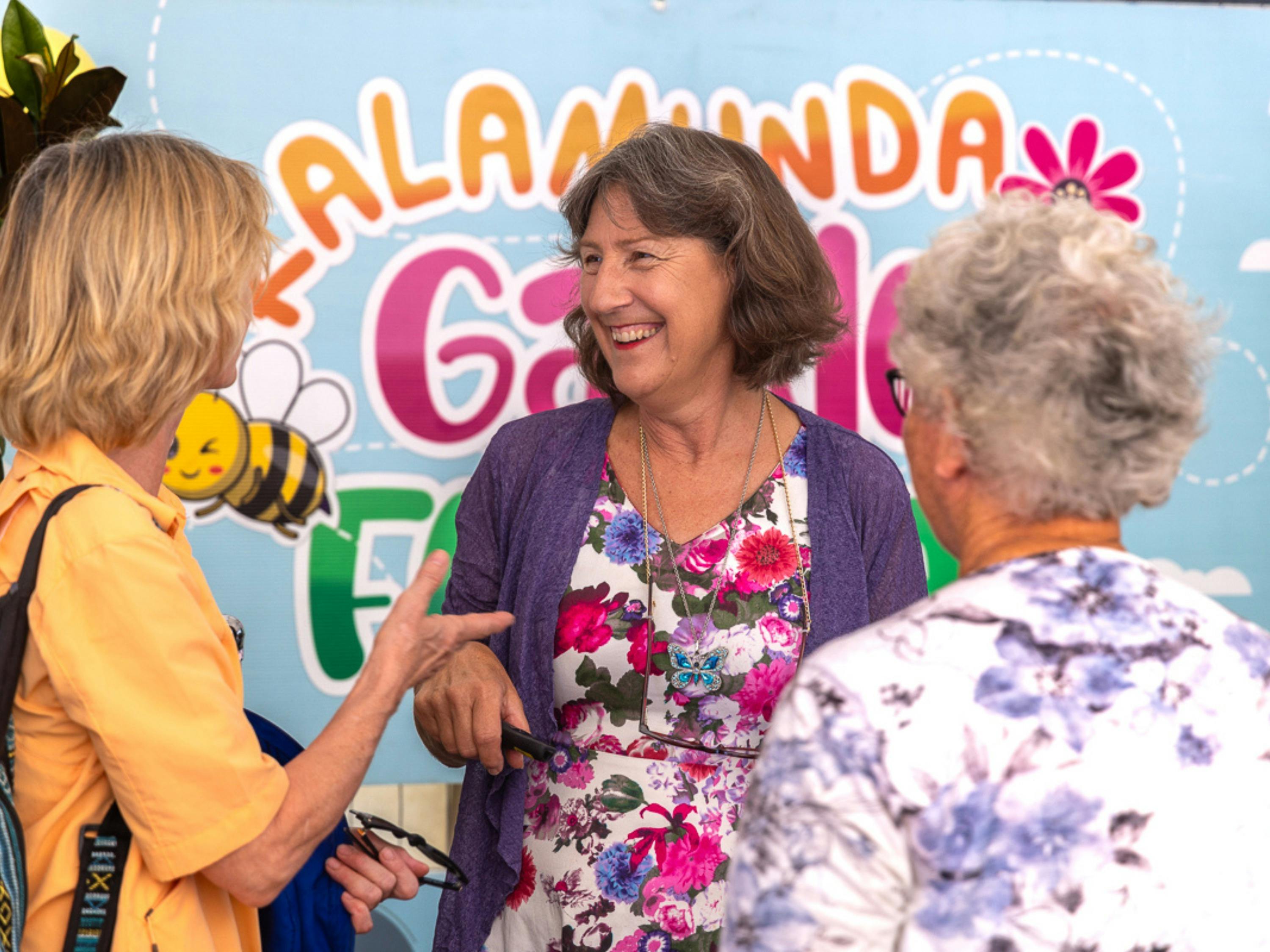 Faye Arcaro chats with festival goers in front of the festival sign.