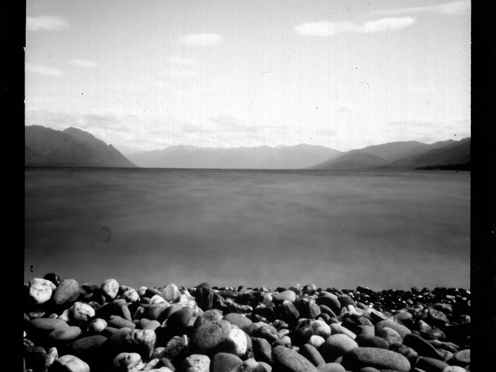 A black and white image of a body of water with a rocky beach