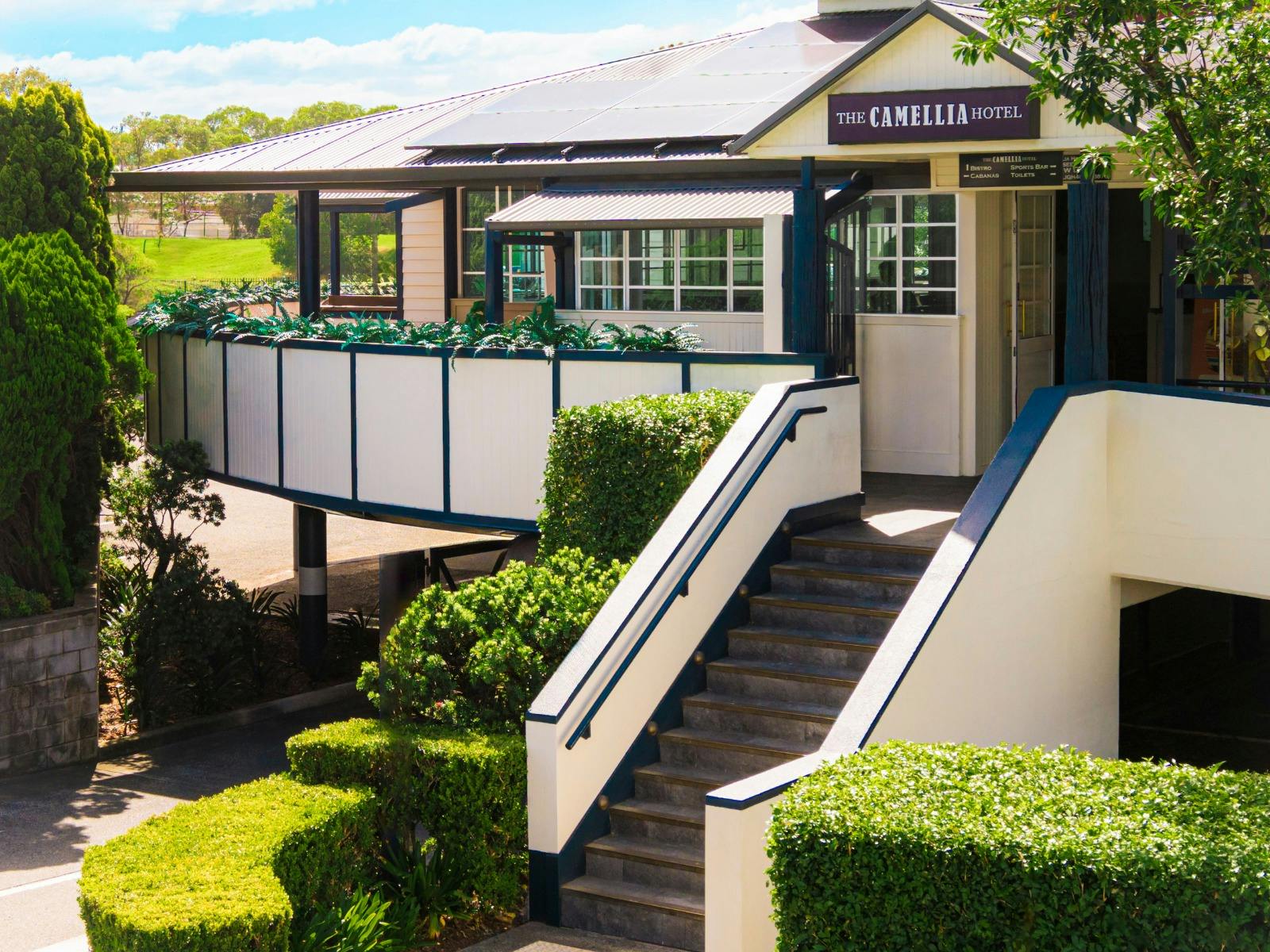 exterior of The Camellia Hotel with signage and stairs